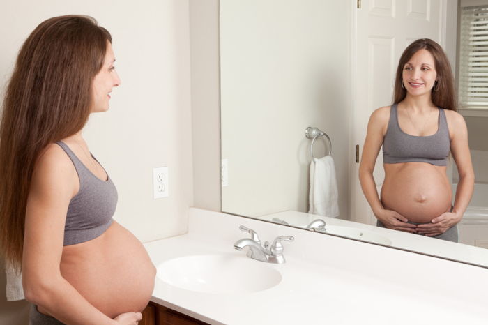 Donna incinta controlla il suo aspetto fisico